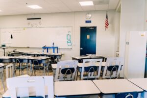 A bright, modern classroom with desks, a whiteboard, and an American flag.